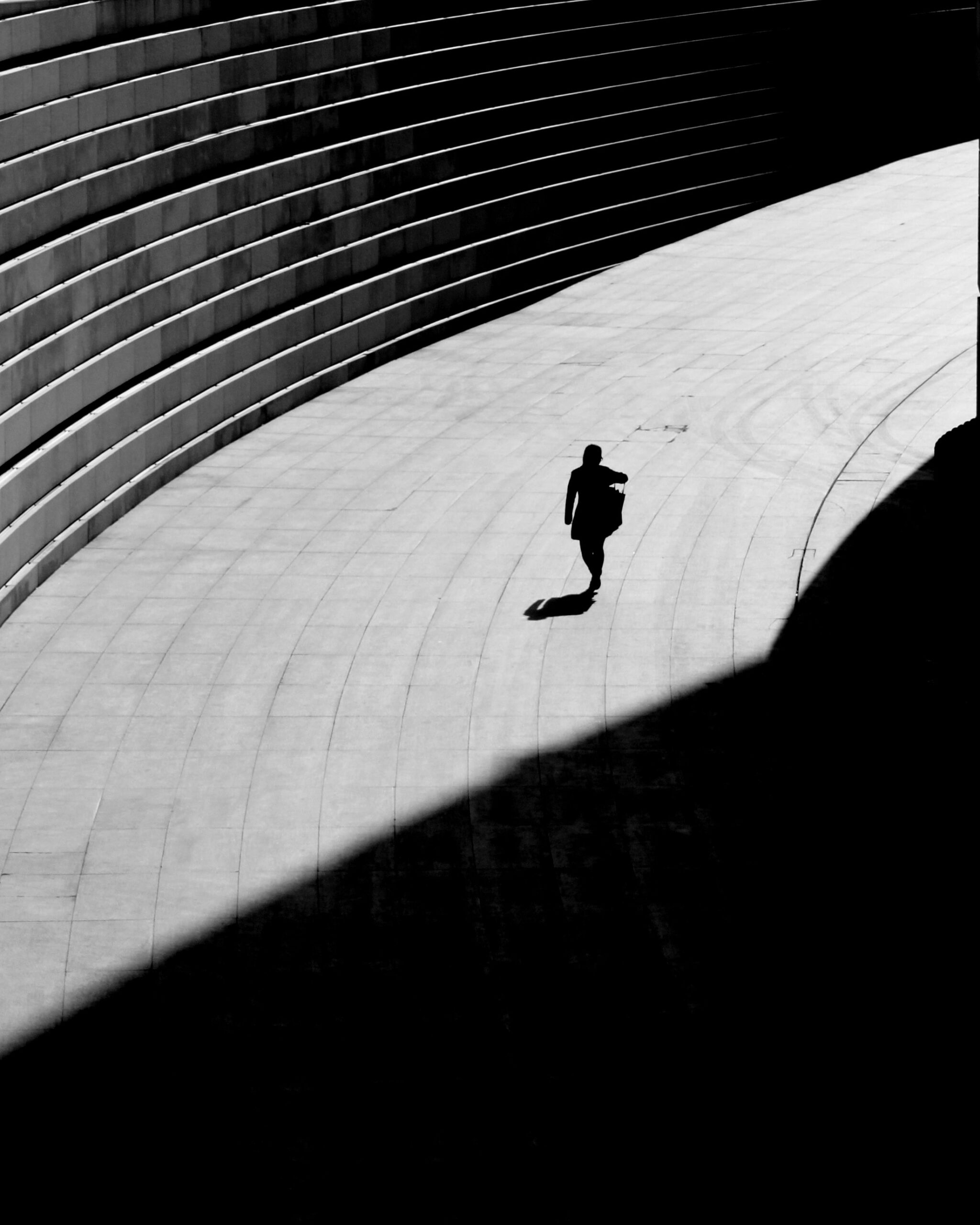 Schatten und Lichtspiel. Frau geht alleine auf Pflaster. Bild in schwarz/weiß. Missbrauchsmuster